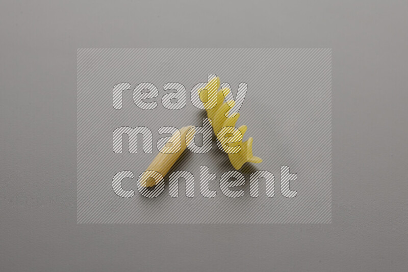 Mini penne pasta with other types of pasta on grey background