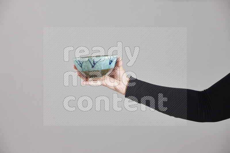 A woman in black abaya holding different pottery essentials in different positions
