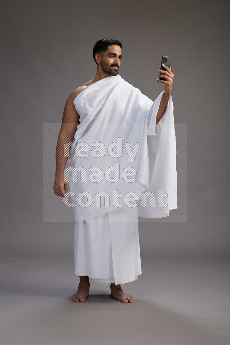A man wearing Ehram Standing taking selfie on gray background