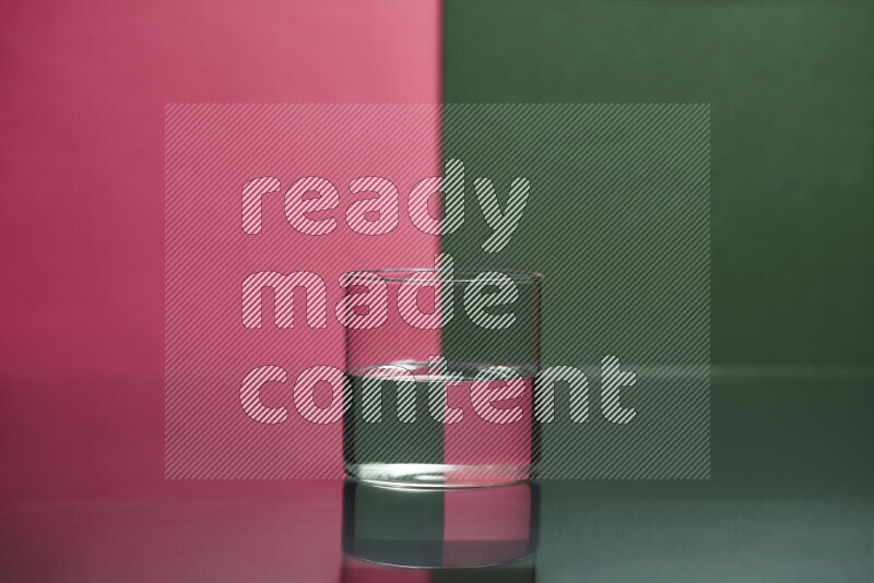 The image features a clear glassware filled with water, set against pink and dark green background