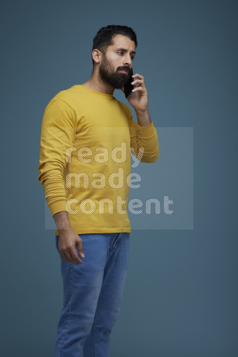 A man having a calling in a blue background wearing a yellow shirt