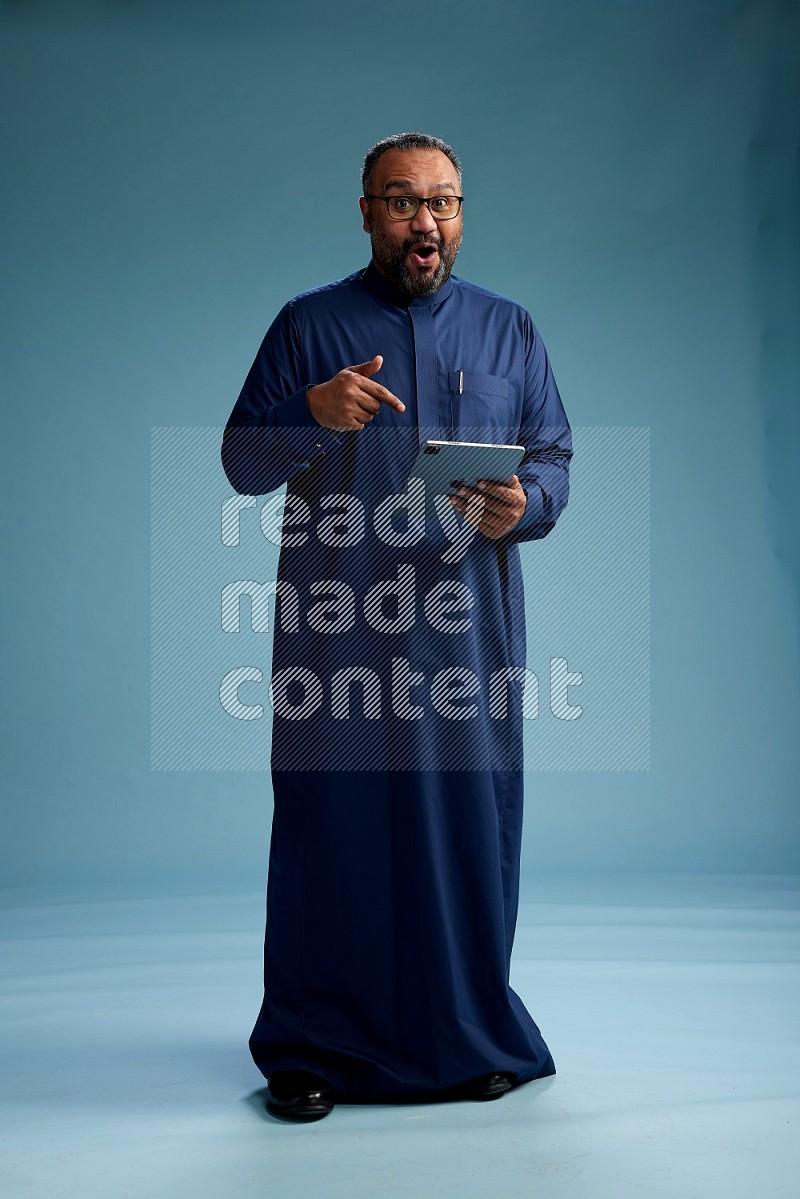 Saudi Man without shimag Standing working on tablet on blue background
