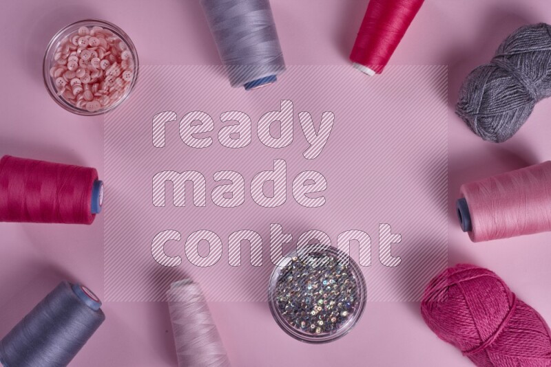 A grey collection of sewing and tailoring tools arranged on a pink background