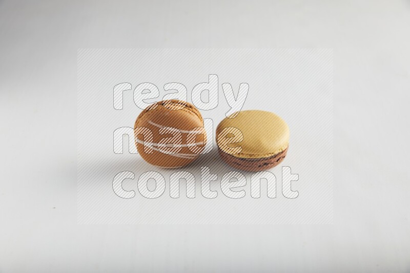 45º Shot of of two assorted Brown Irish Cream, and Yellow, and Brown Chai Latte macarons on white background
