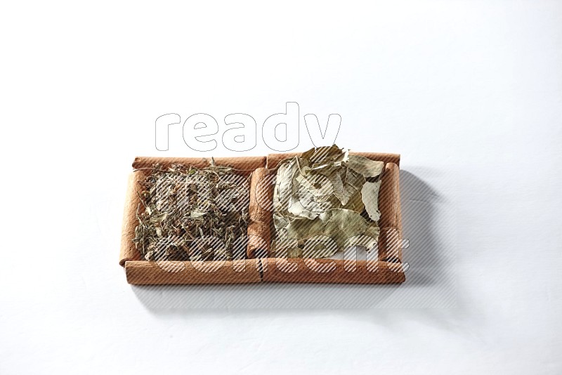 2 squares of cinnamon sticks full of dried basil and bay laurel leaves on white flooring