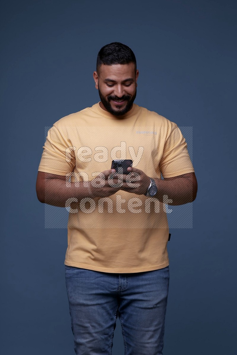 A man Texting on his phone in Blue Background wearing Orange T-shirt