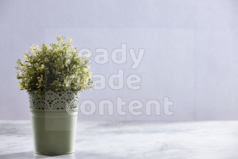 Artificial plant in green decorative pot on grey marble background