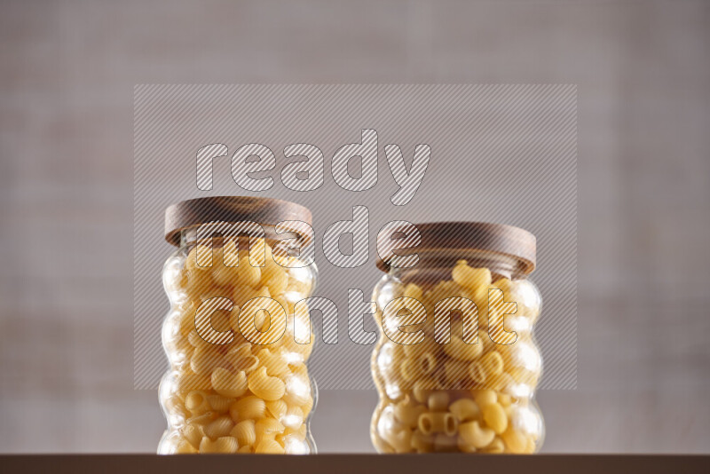 Raw pasta in glass jars on beige background