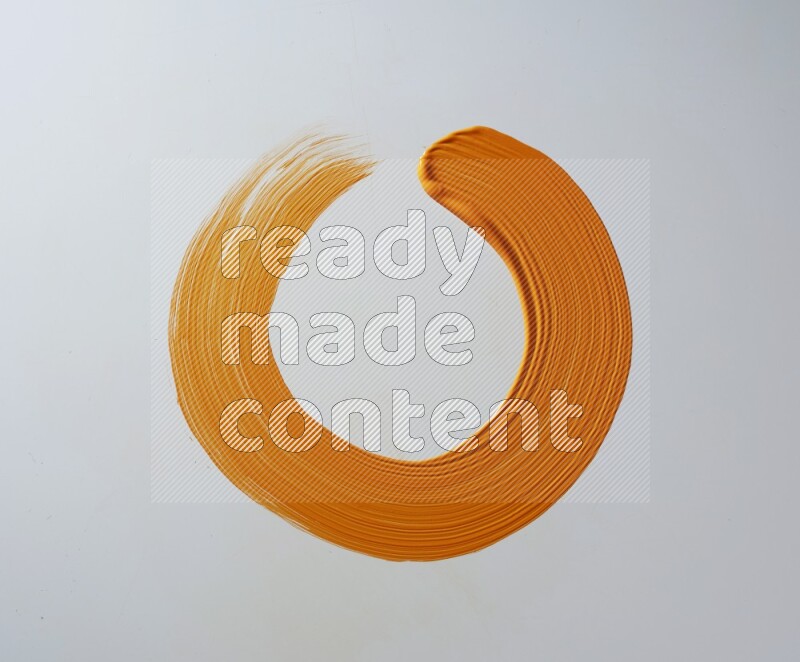 An orange circular painting brush stroke on white background