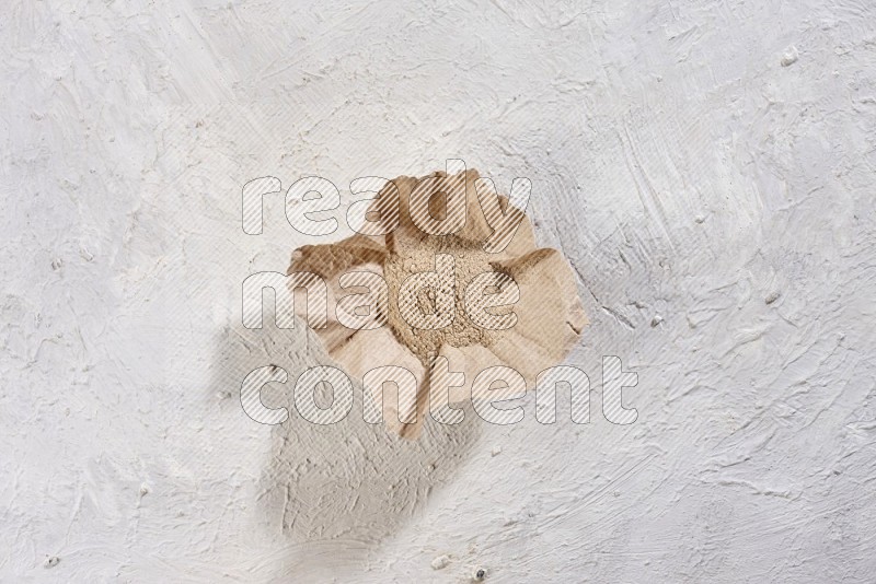 A crumpled piece of paper full of garlic powder on a textured white flooring in different angles