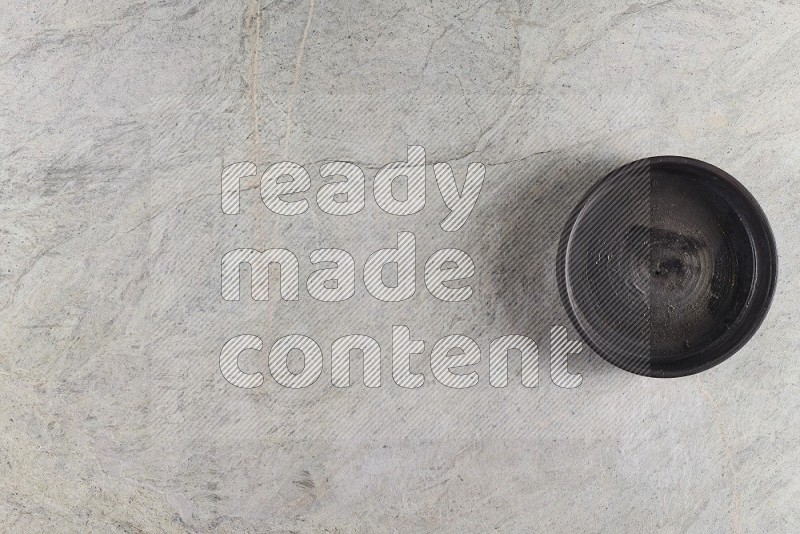 Top View Shot Of A Black Pottery Oven Plate On Grey Marble Flooring