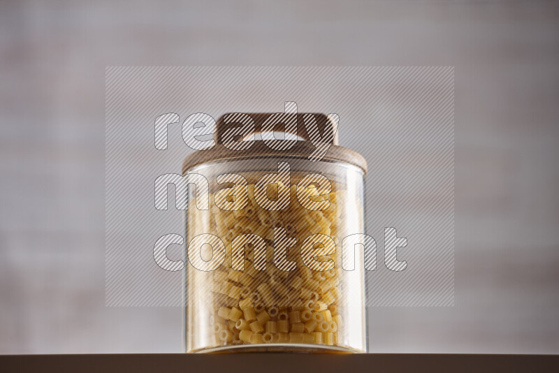 Raw pasta in glass jars on beige background