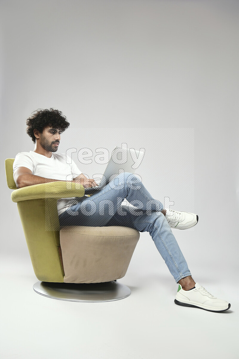 A man wearing casual sitting on a chair working on a laptop on white background