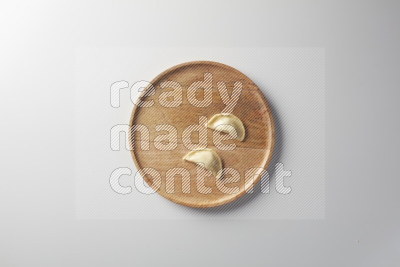 Two Sambosas on a wooden round plate on a white background