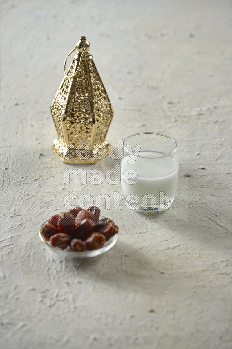 A golden lantern with different drinks, dates, nuts, prayer beads and quran on textured white background