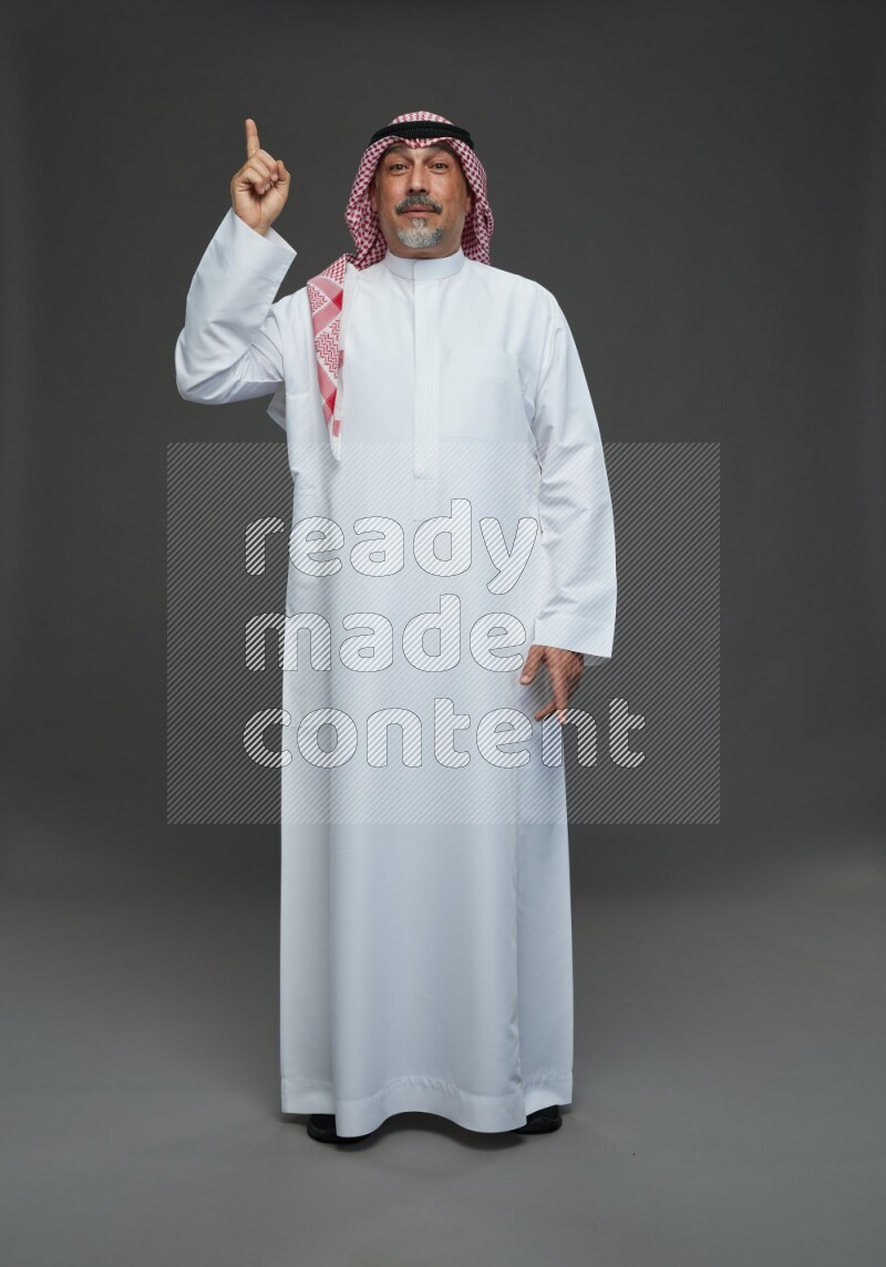 Saudi man with shomag Standing Interacting with the camera on gray background