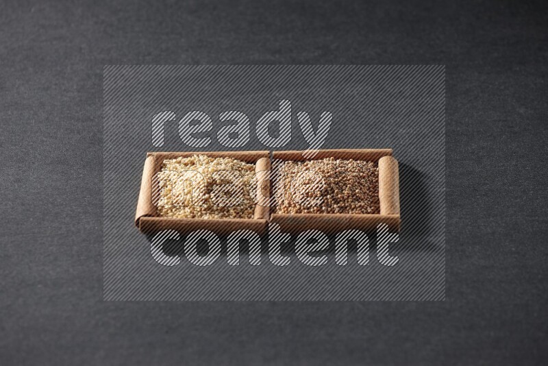 مربعان من أعواد القرفة ممتلئان بحبوب الخردل وبذور السمسم علي خلفية سوداء