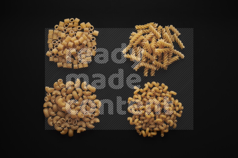 Different pasta types in bunches on black background