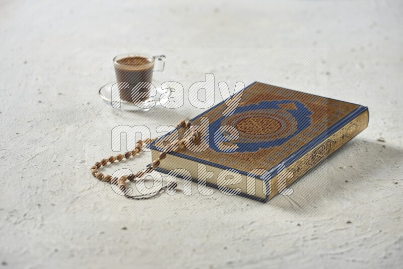 Quran with dates, prayer beads and different drinks all placed on textured white background