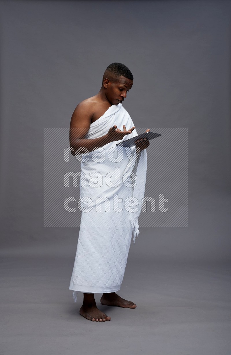 A man wearing Ehram Standing working on tablet on gray background