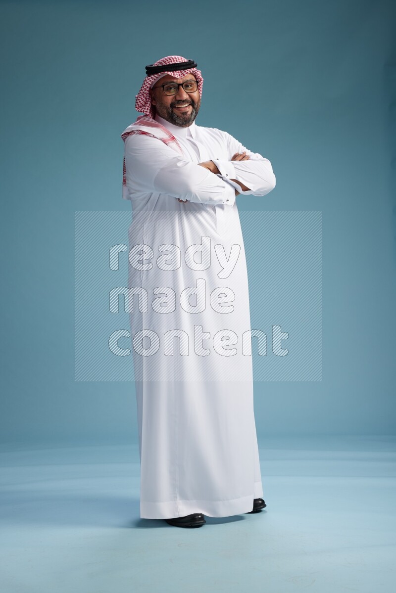 Saudi Man with shimag Standing Interacting with the camera on blue background