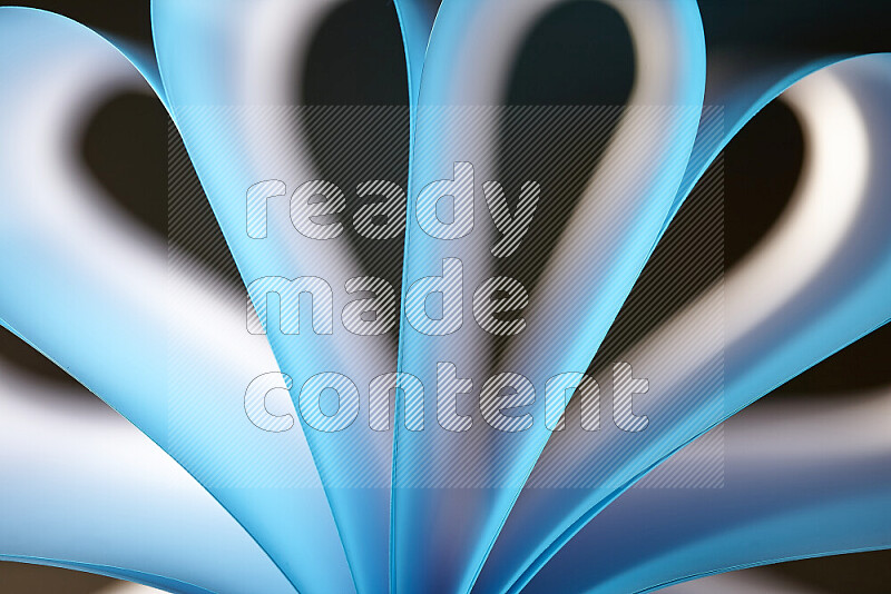 An abstract art piece displaying smooth curves in white and blue gradients created by colored light