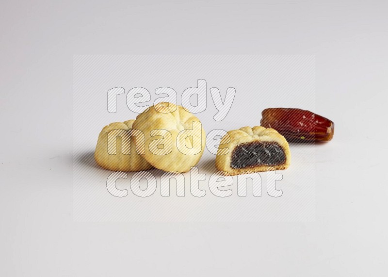 Three Pieces of Maamoul filled with date one of them is cut direct on white background