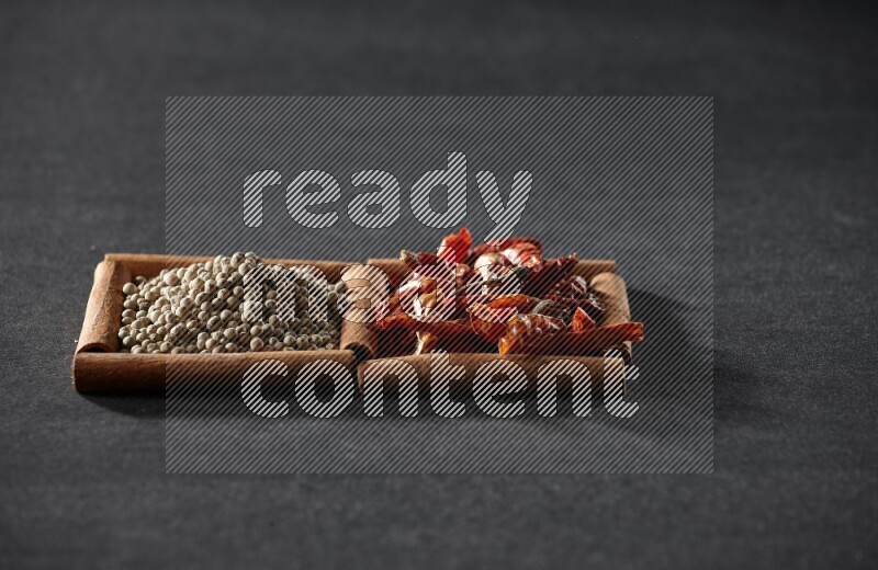 2 squares of cinnamon sticks full of chilis and white peppers on black flooring