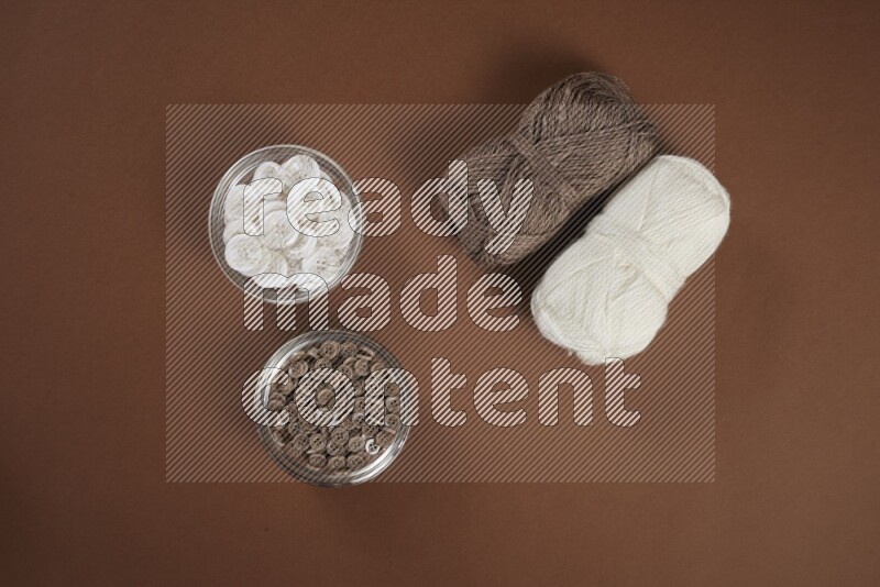 مجموعة من أدوات الخياطة والتفصيل بيضاء وبنية اللون على خلفية بنية