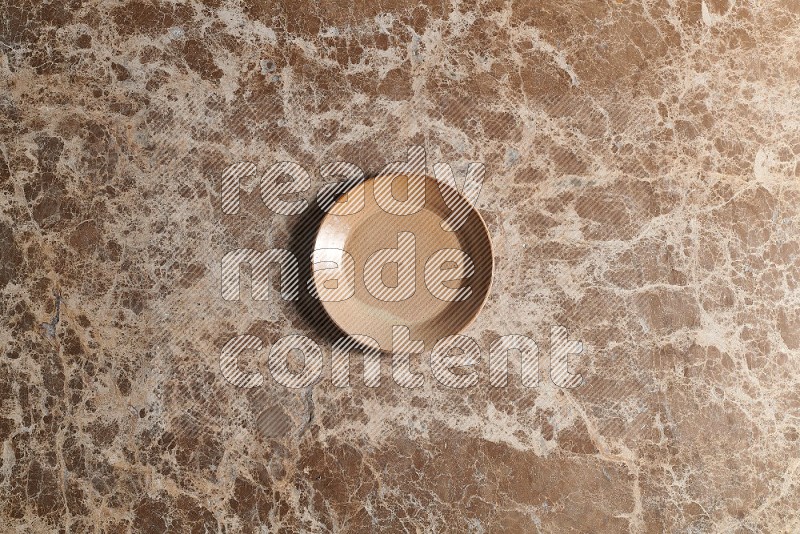Top View Shot Of A Beige Pottery Circular Plate On beige Marble Flooring