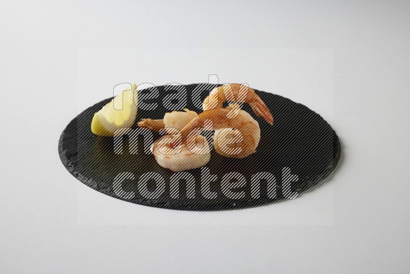 four grilled shrimp  on a black slate direct  on a white back ground
