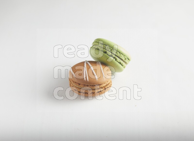 45º Shot of of two assorted Brown Irish Cream, and Green Pistachio macarons on white background