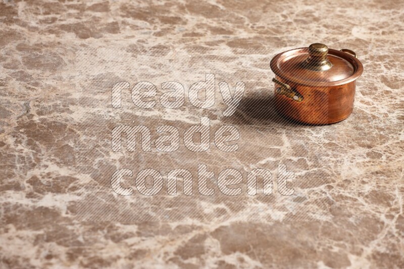A small copper pot on beige marble background
