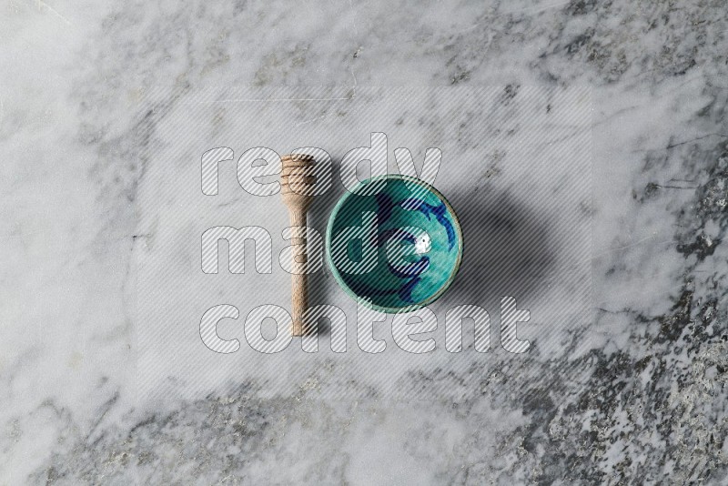 Decorative Pottery Bowl with wooden honey handle on the side on grey marble flooring, Top view