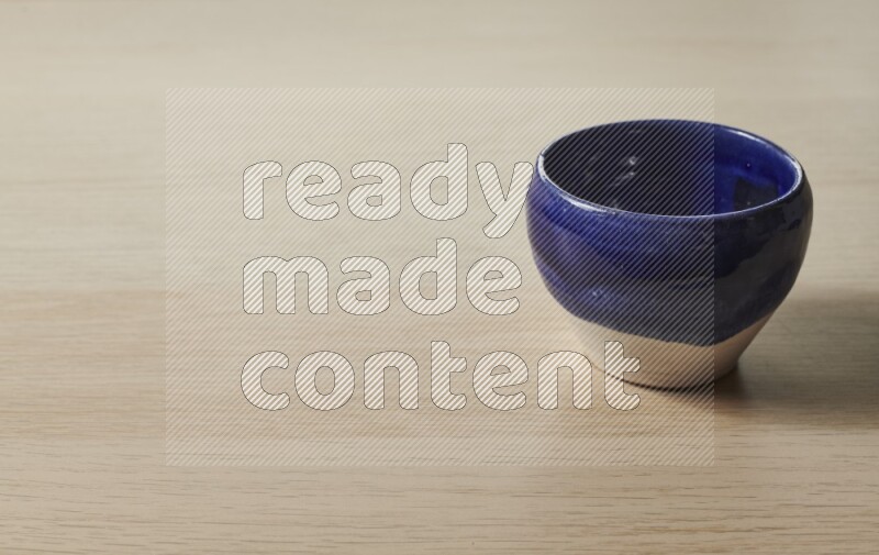 A multicolored pottery bowl on light wooden background