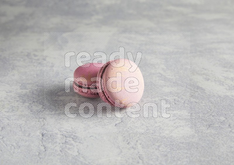 45º Shot of two Purple Strawberry macarons on white  marble background