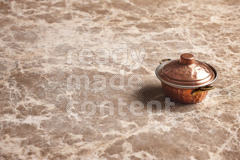 A small copper pot on beige marble background