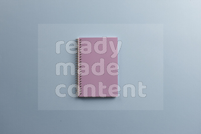 A purple notebook with different school supplies on blue background