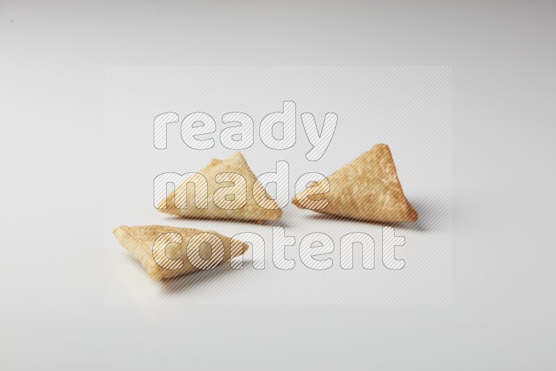 Three fried sambosas on a white background
