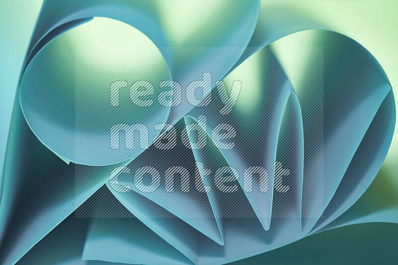 An artistic display of paper folds creating a harmonious blend of geometric shapes, highlighted by soft lighting in green and blue tones