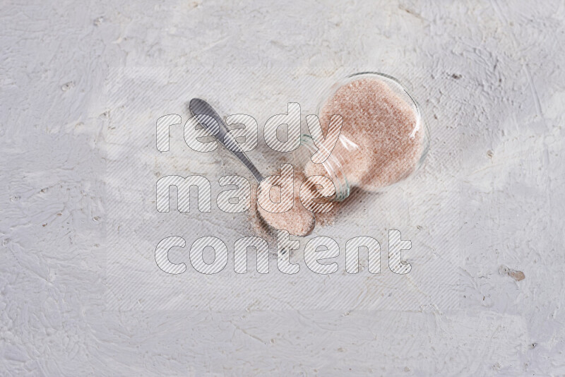 A glass jar full of fine himalayan salt on white background