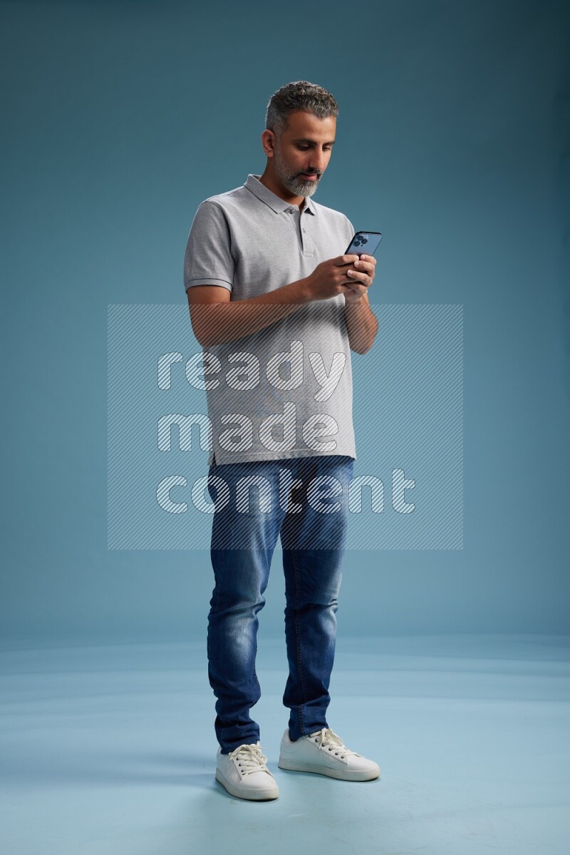 Man Standing texting on phone on blue background