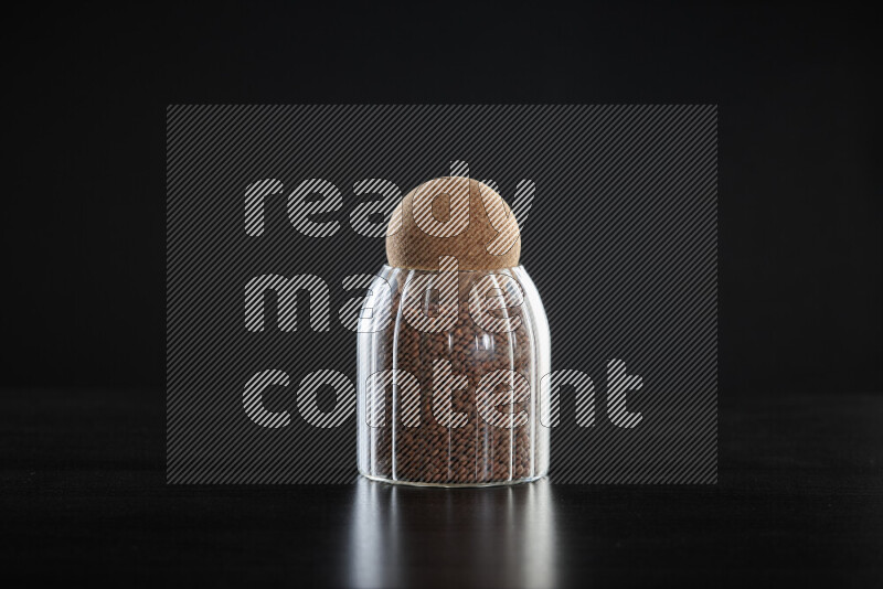 Brown lentils in a glass jar on black background