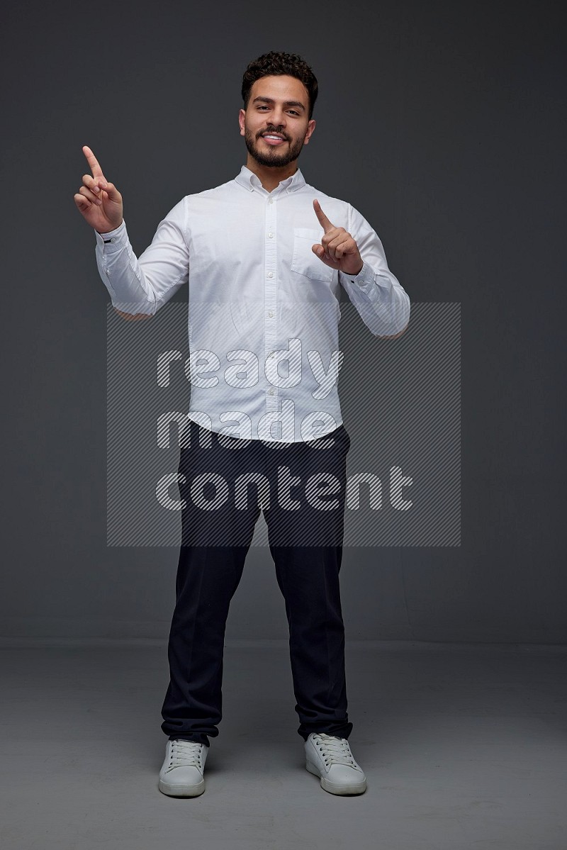 A man wearing smart casual standing and making multi hand gestures eye level on a gray background