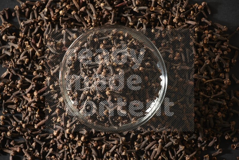 A glass bowl full of cloves on a black flooring