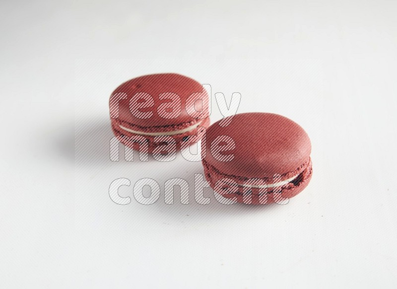 45º Shot of two Red Velvet macarons on white background