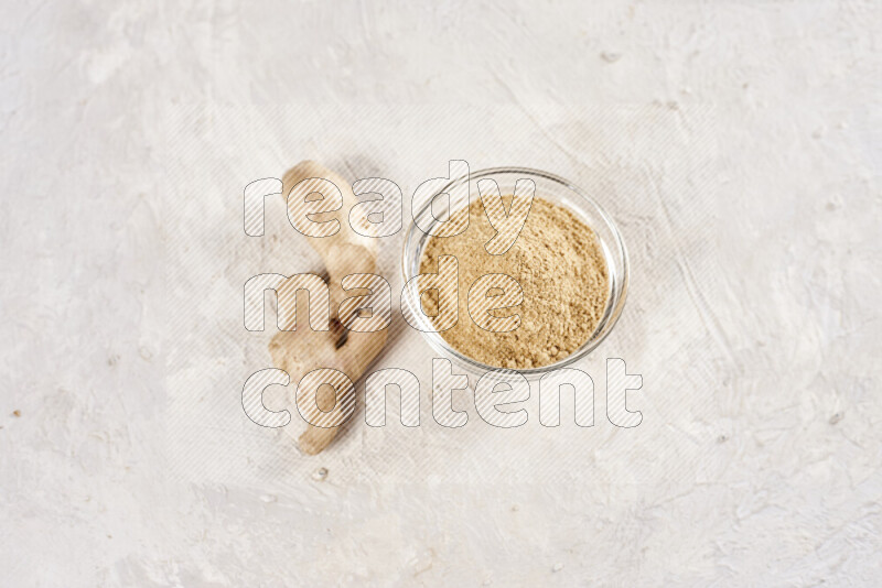 A glass bowl full of ground ginger powder on white background