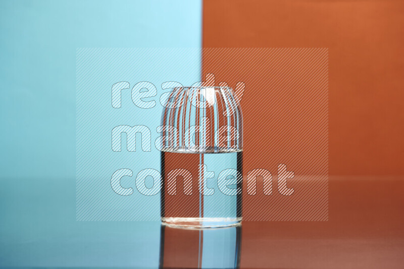 The image features a clear glassware filled with water, set against light blue and dark orange background