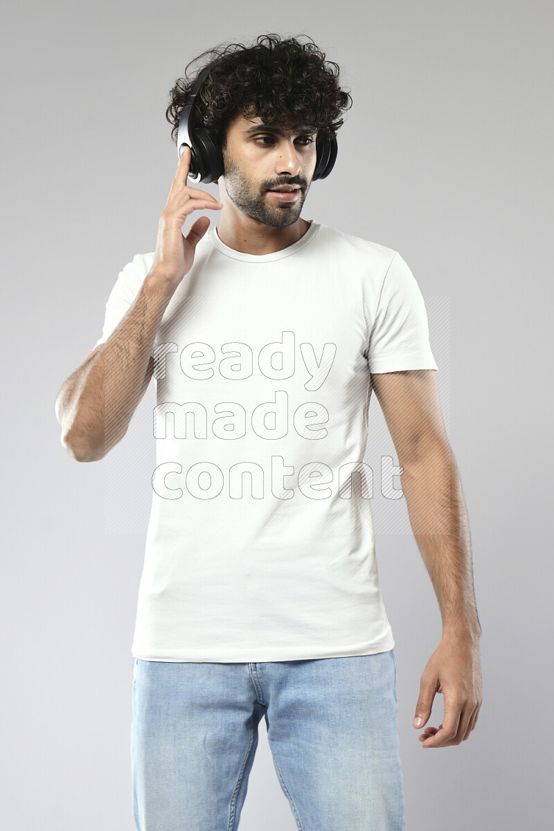 رجل يرتدي ملابس كاجوال يضع سماعات رأس علي خلفية بيضاء