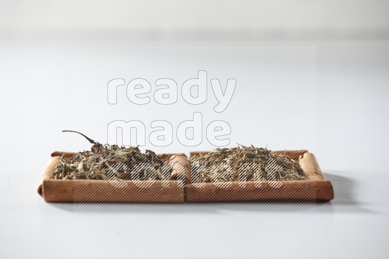 2 squares of cinnamon sticks full of dried basil and cumin on white flooring